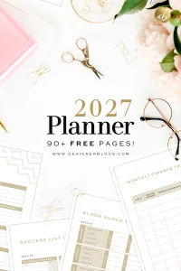 Preview of the free 2027 printable planner showing printed pages for a grocery list, blood sugar log, and monthly finance tracker . The pages are styled on a white desk with gold scissors, wire paper clips, reading glasses, and pink flowers